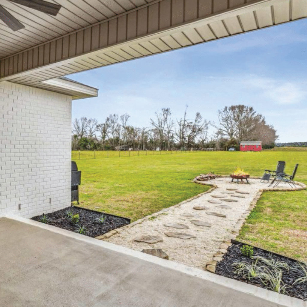 Backyard patio with stone pathway leading to a fire pit and seating area.